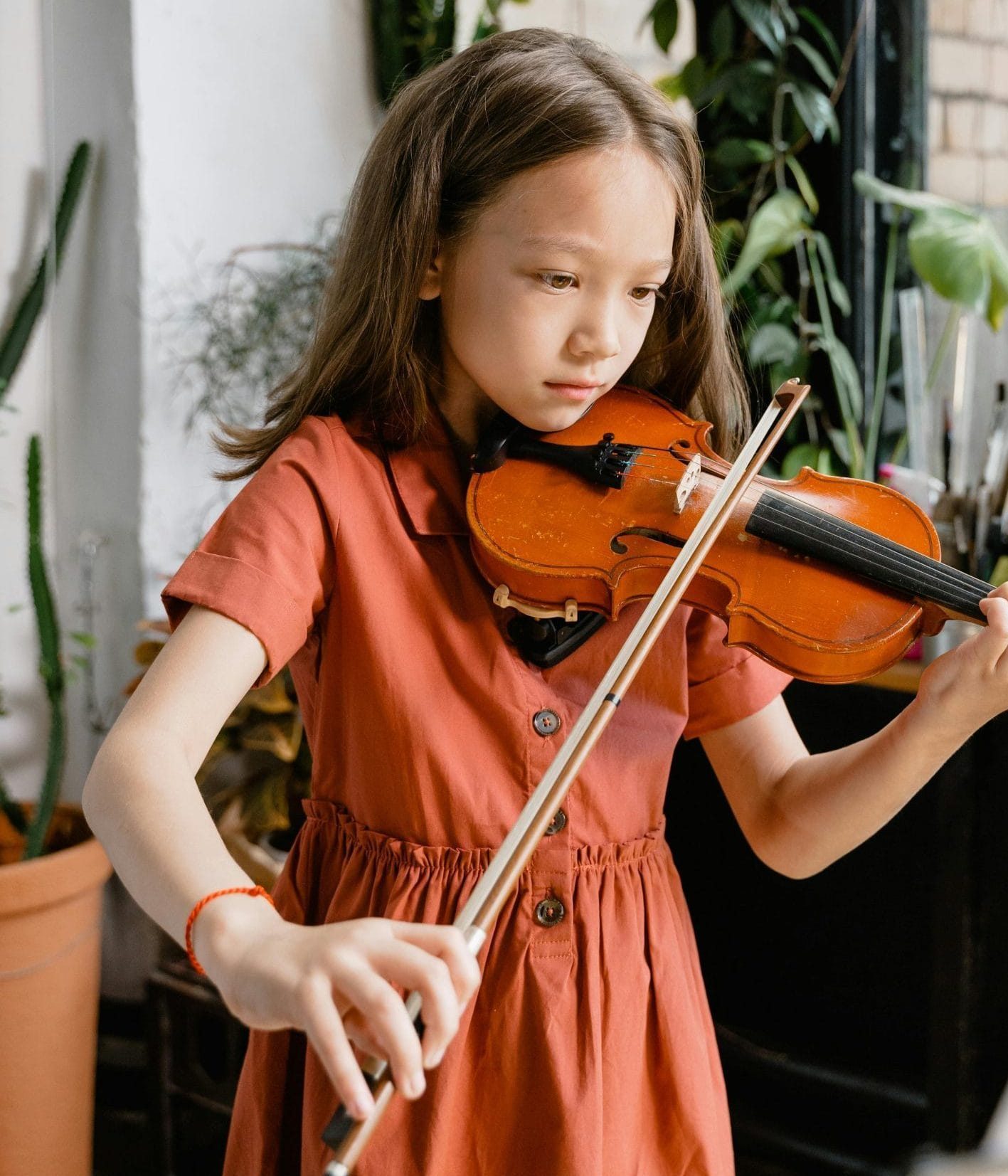 Fille jouant du violon à l'intérieur.